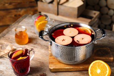 Photo of Delicious mulled wine and ingredients on wooden table