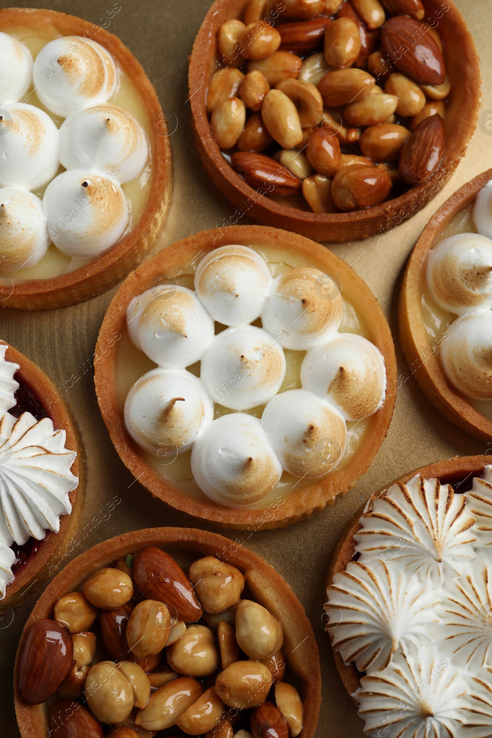 Photo of Many different tartlets on golden tray, top view. Delicious dessert