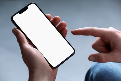 Photo of Man holding smartphone with blank screen on light grey background, closeup. Mockup for design