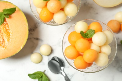 Flat lay composition with melon balls and mint on white marble table