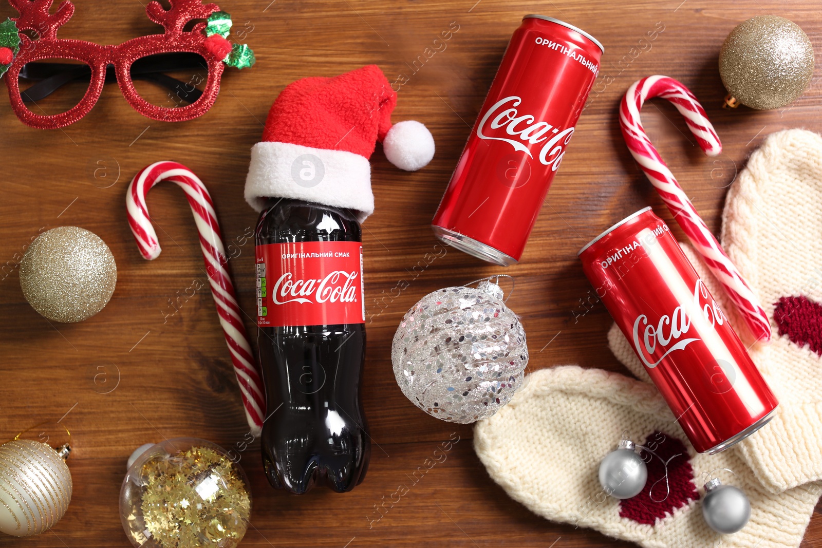 Photo of MYKOLAIV, UKRAINE - January 01, 2021: Flat lay composition with Coca-Cola drinks and Christmas decorations on wooden background