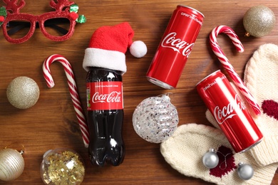 MYKOLAIV, UKRAINE - January 01, 2021: Flat lay composition with Coca-Cola drinks and Christmas decorations on wooden background