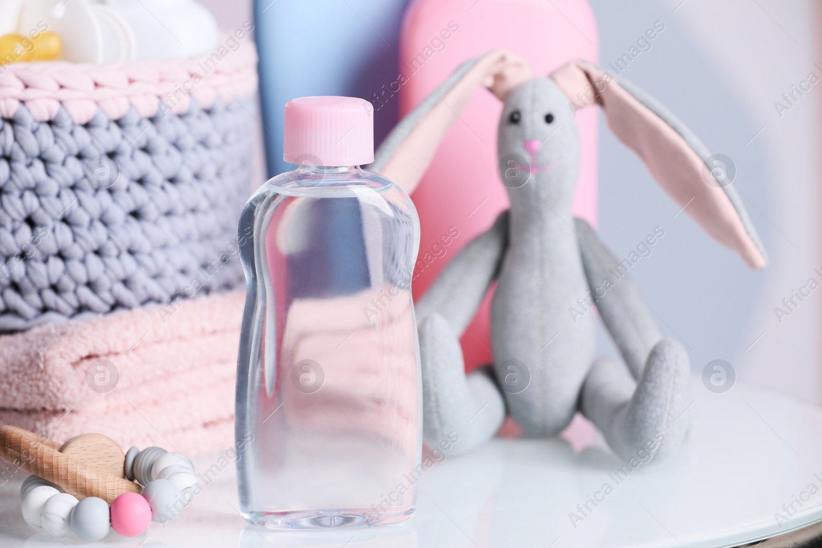 Photo of Bottle of baby cosmetic product, toys and accessories on white table against color background. Space for text