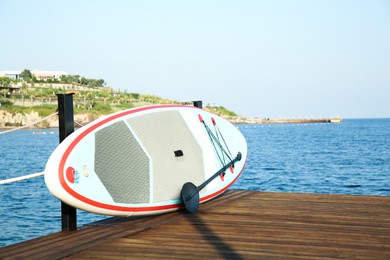 SUP board with paddle on wooden pier near sea