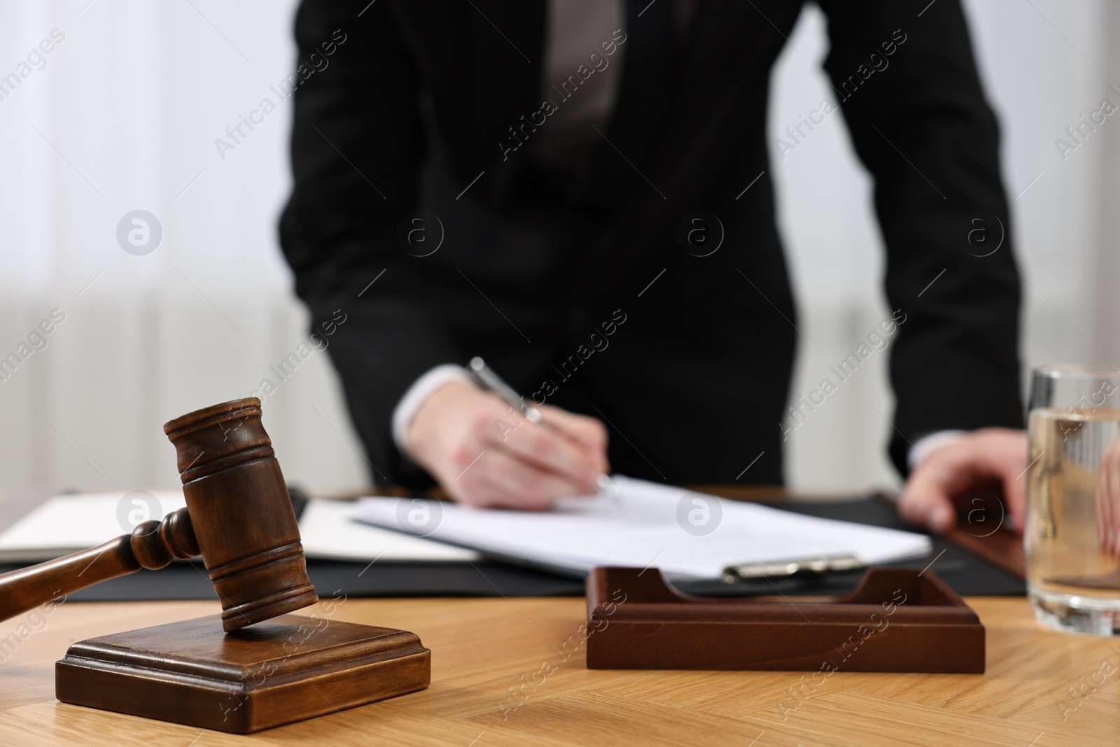 Photo of Lawyer working with documents at wooden table, focus on gavel