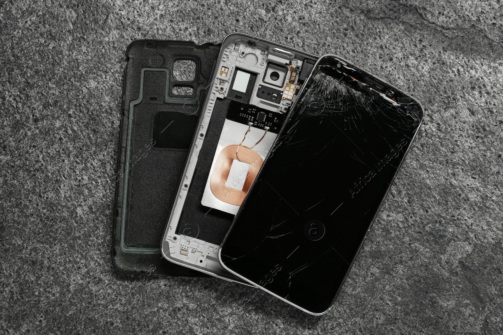 Photo of Damaged smartphone on grey background, flat lay. Device repairing