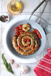 Photo of Delicious homemade sausage with garlic, tomatoes, rosemary and chili served on light tiled table, flat lay