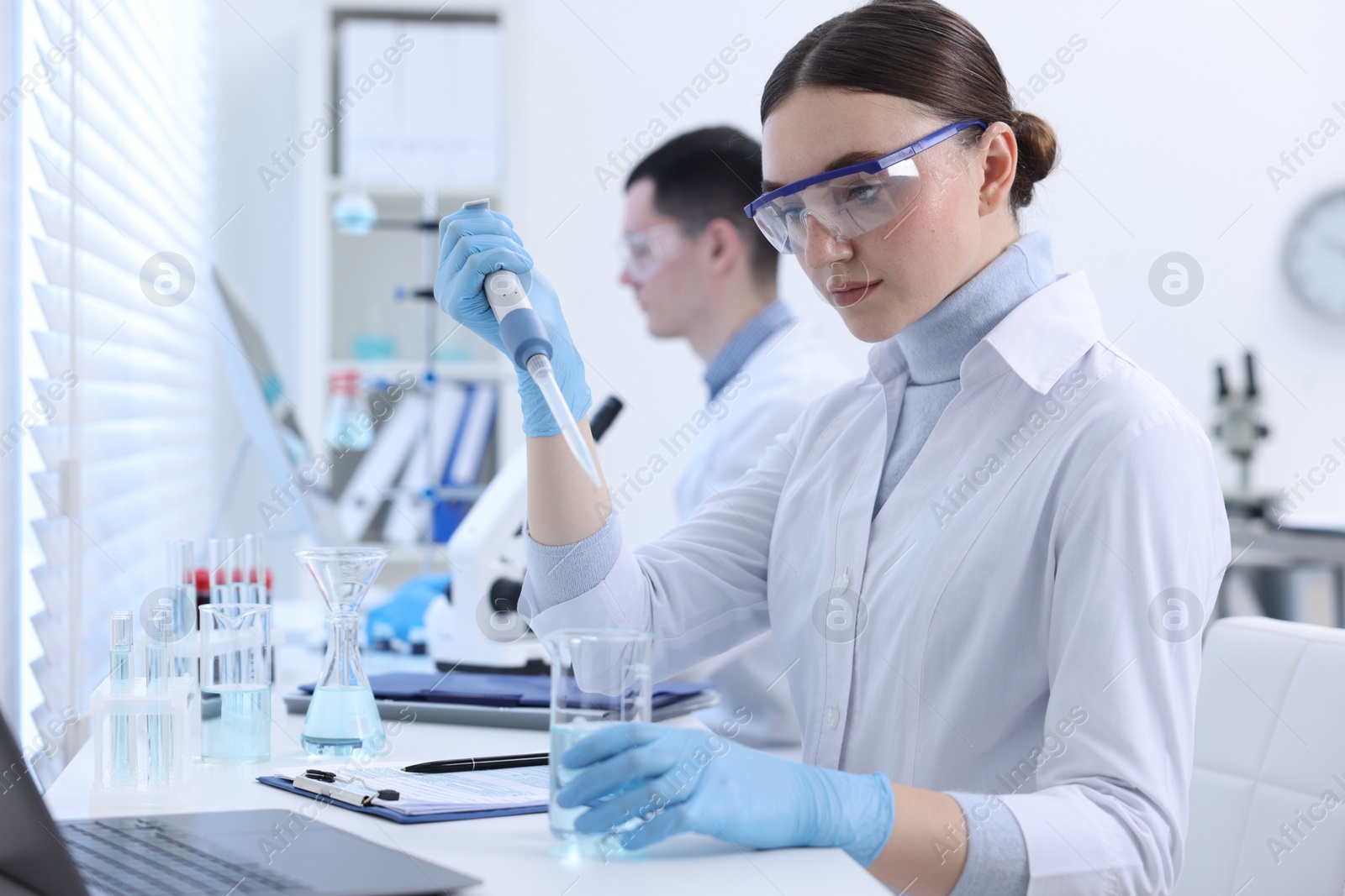 Photo of Scientist dripping sample into beaker in laboratory