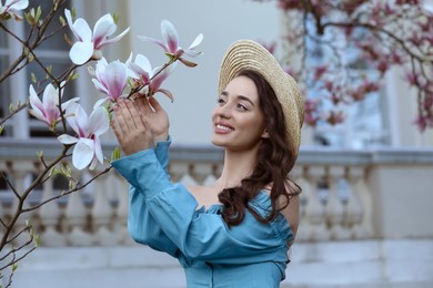Photo of Beautiful woman touching blossoming magnolia tree branch on spring day