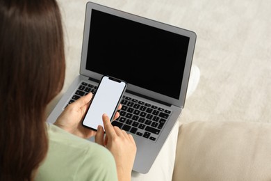 Photo of Young woman with smartphone and laptop indoors, closeup