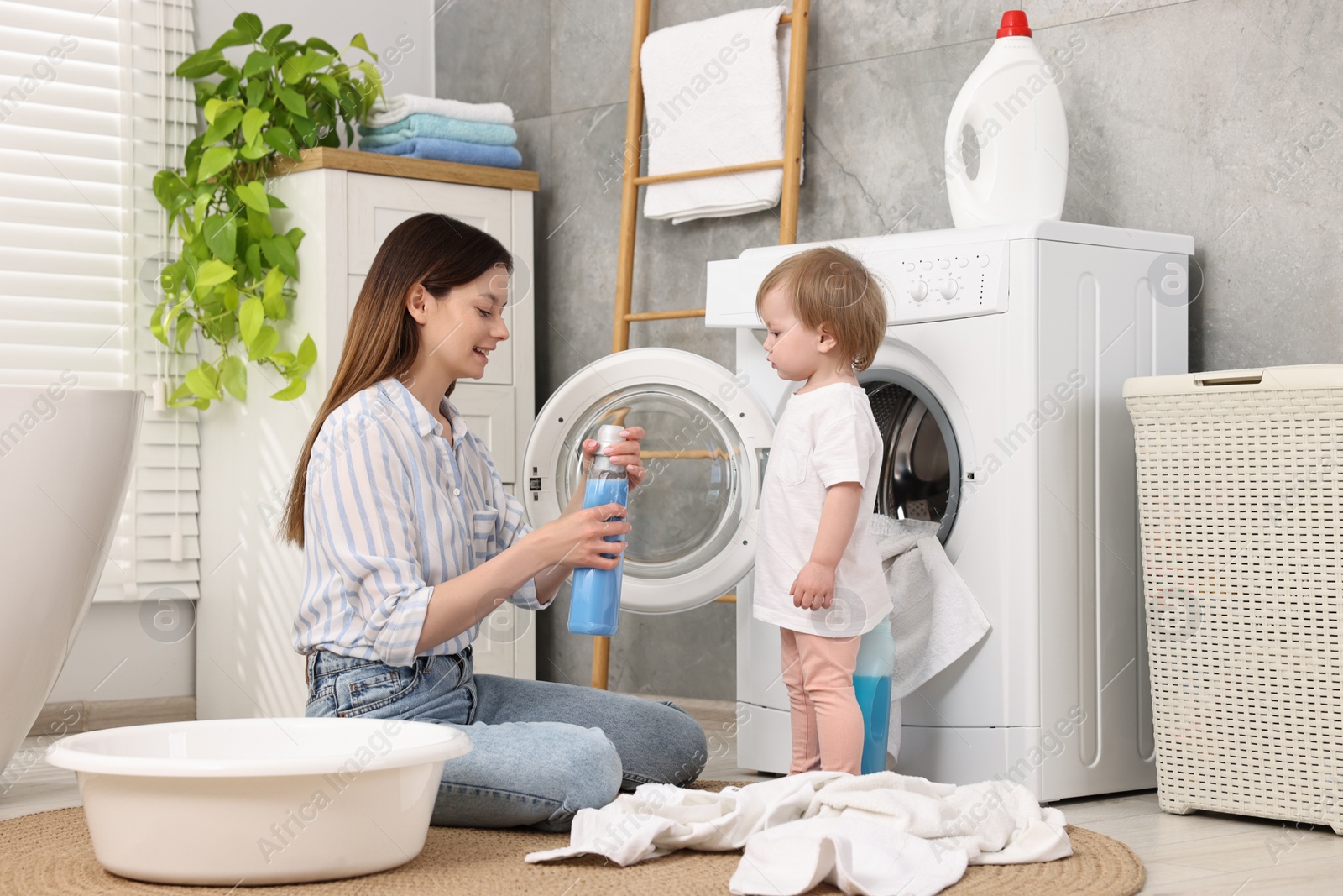 Photo of Mother with her daughter washing baby clothes in bathroom