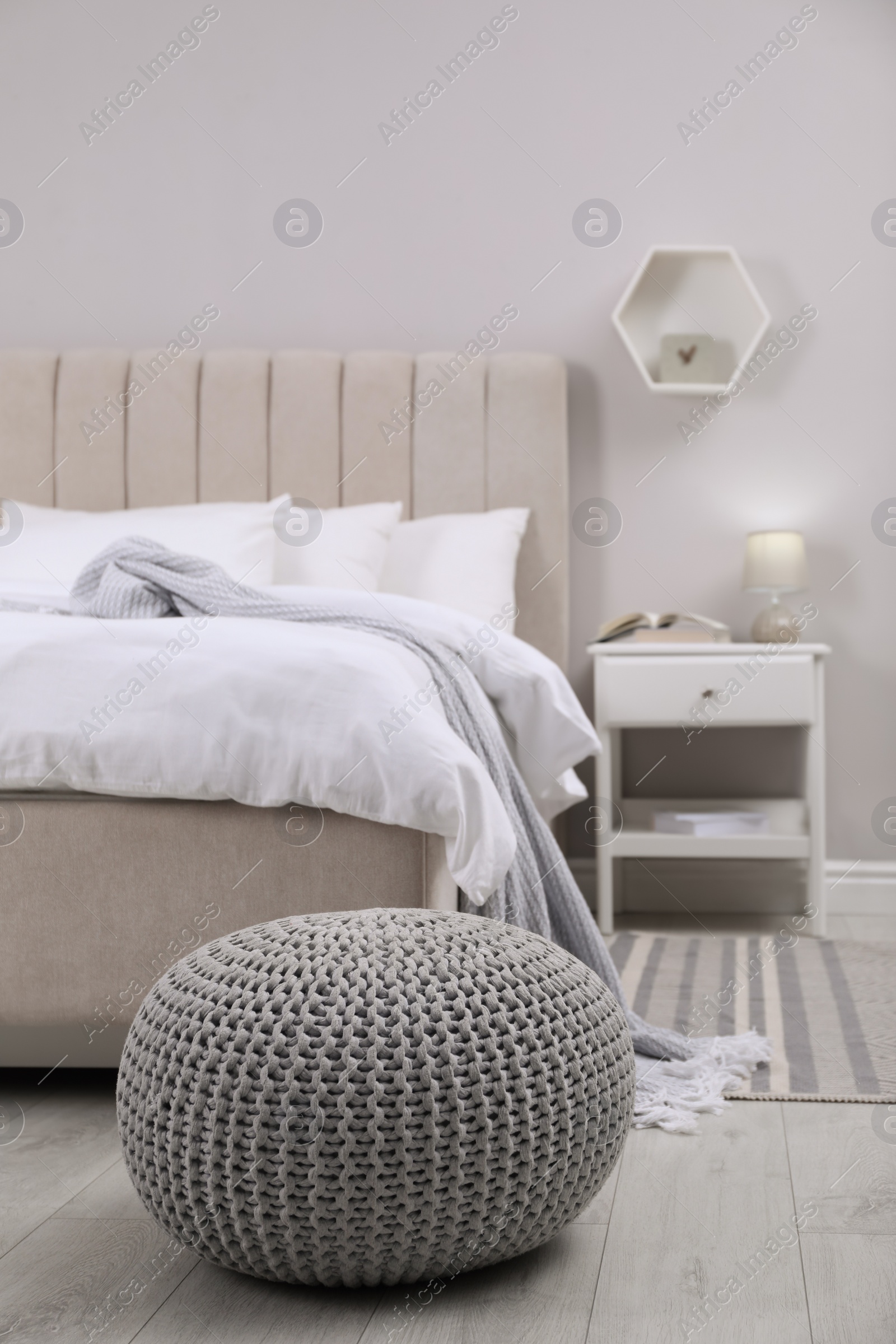 Photo of Stylish bedroom interior with knitted pouf and furniture