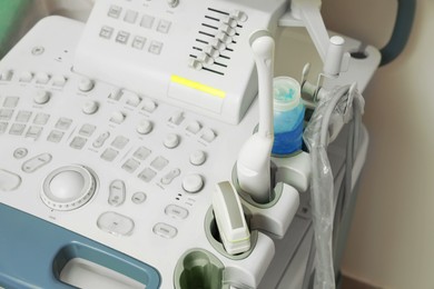 Photo of Ultrasound control panel with ultrasonic transducers and transmission gel near white wall, closeup