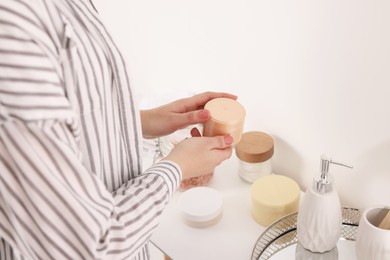 Photo of Bath accessories. Woman with jar of cosmetic product indoors, closeup