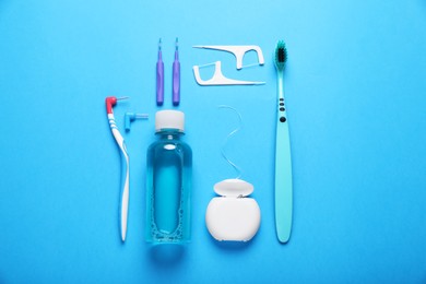 Photo of Dental floss and different teeth care products on light blue background, flat lay