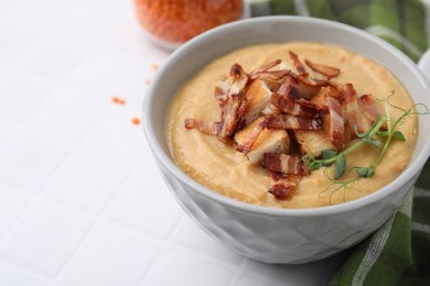 Photo of Delicious lentil soup with bacon and croutons on white tiled table, closeup. Space for text