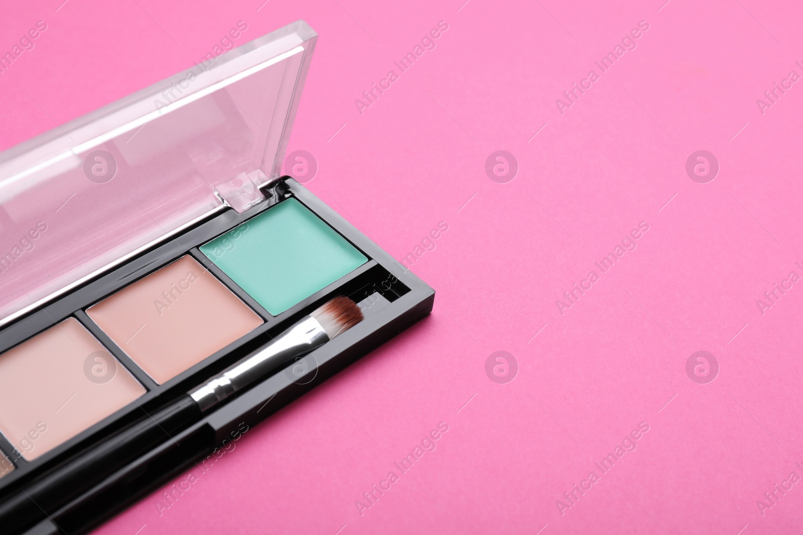 Photo of Colorful contouring palette and brush on pink background, closeup with space for text. Professional cosmetic product
