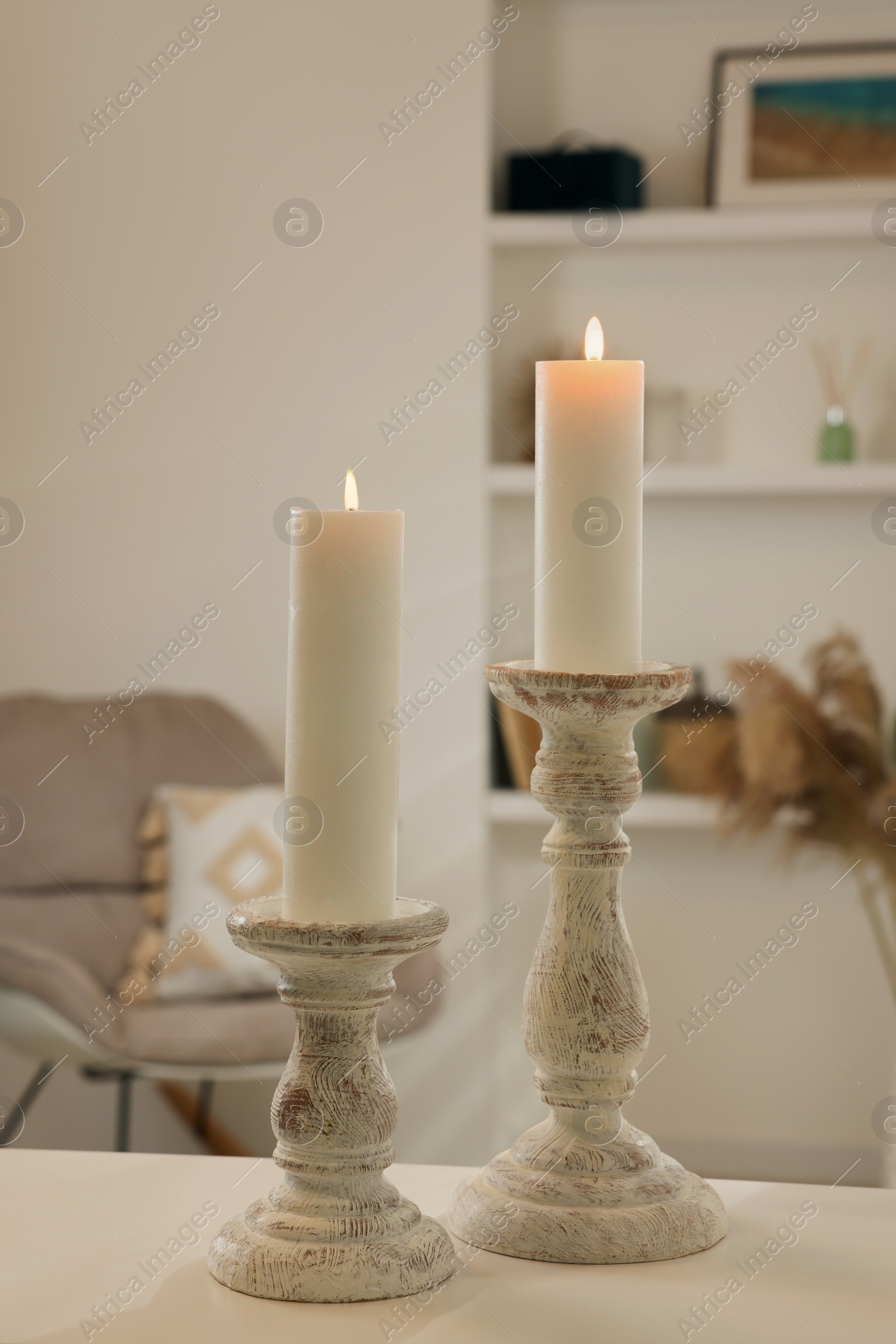 Photo of Beautiful wooden candlesticks on white table in room