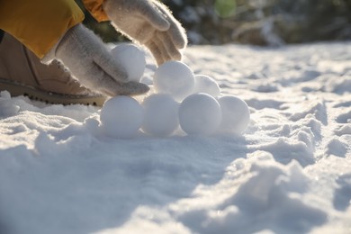 Photo of Woman rolling snowballs outdoors on winter day, closeup