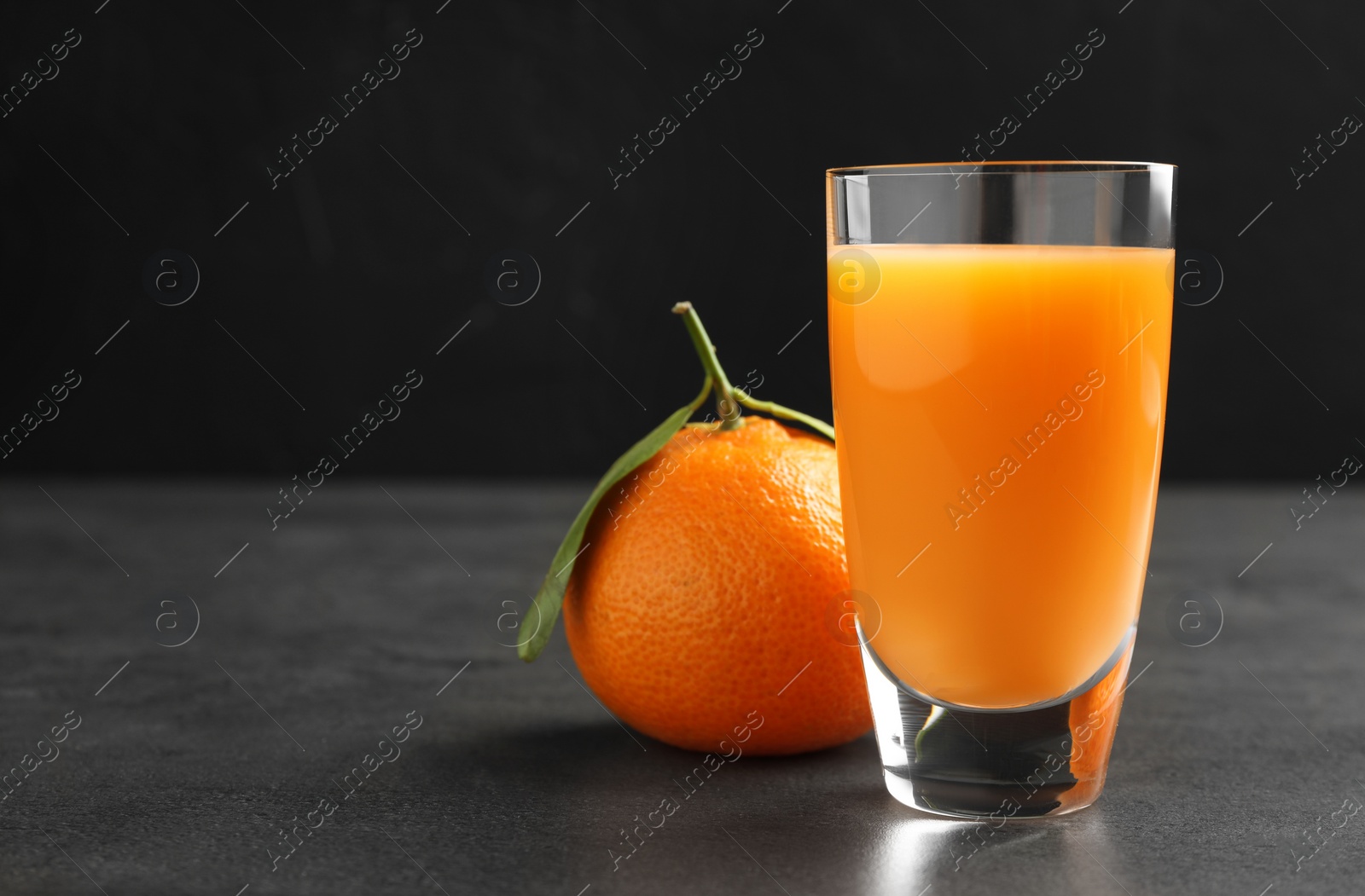 Photo of Delicious tangerine liqueur and fresh fruit on grey table, space for text