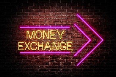 Money Exchange neon sign on brick wall. Bright yellow text and pink arrow