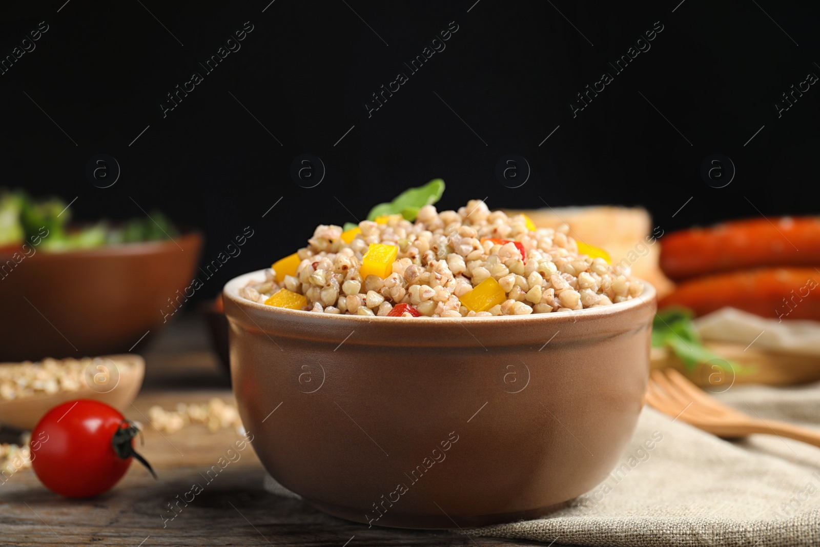 Photo of Tasty buckwheat porridge with vegetables on wooden table