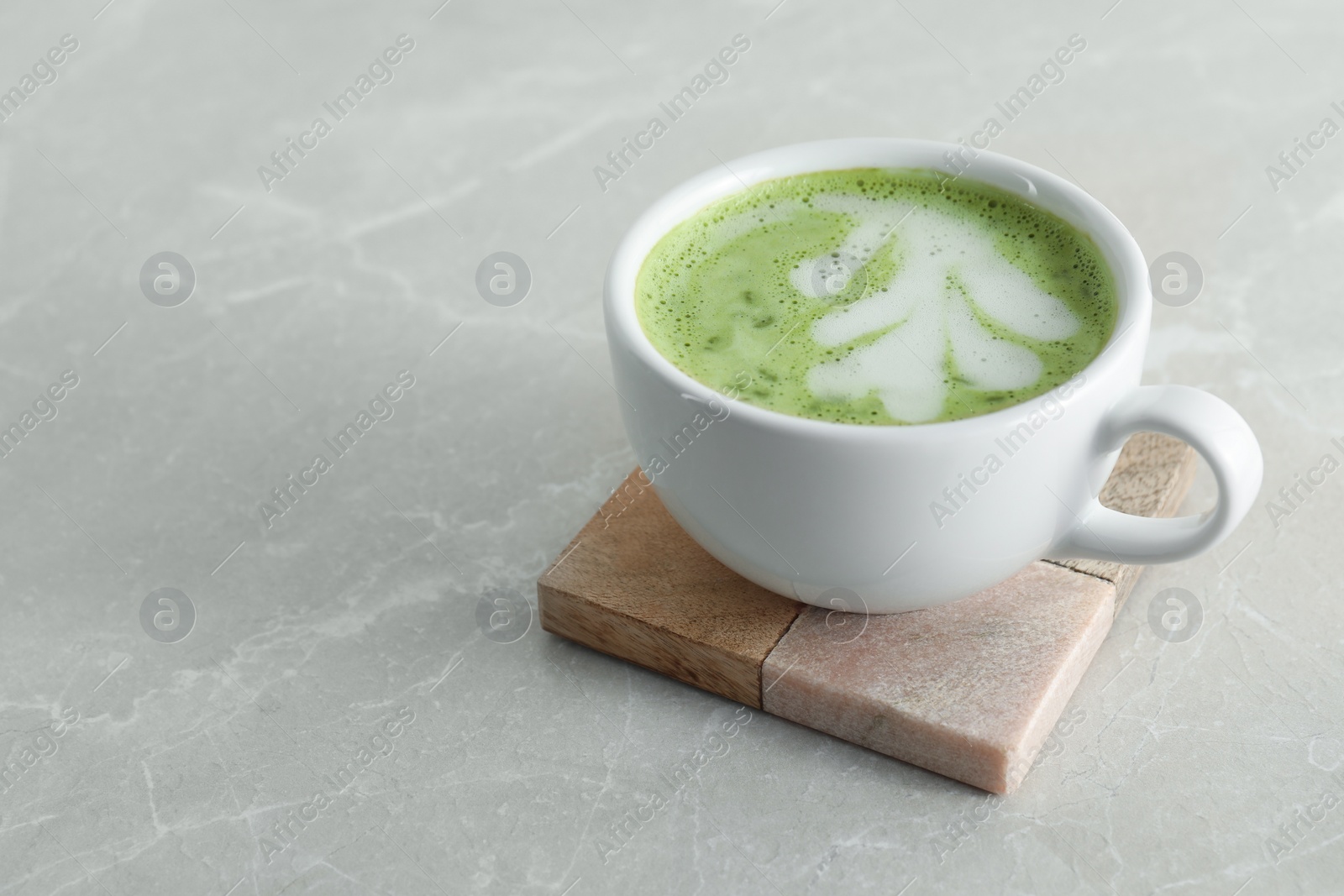 Photo of Cup of fresh matcha latte on light grey marble table. Space for text