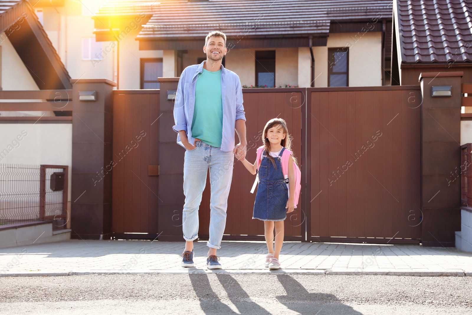 Image of Happy father taking his little child to school on street