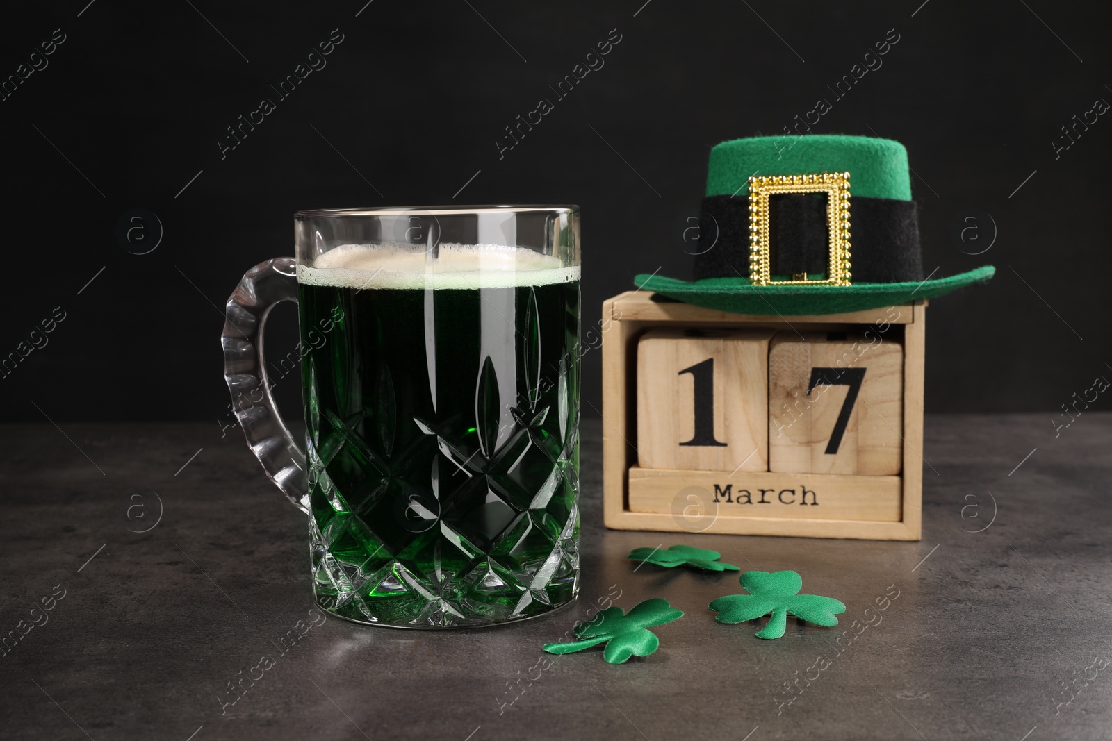 Photo of St. Patrick's day celebrating on March 17. Green beer, wooden block calendar, leprechaun hat and decorative clover leaves on grey table