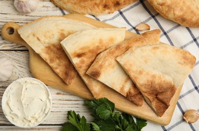 Photo of Cut pita bread, cream cheese and parsley on white wooden table, flat lay