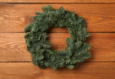 Photo of Christmas wreath made of fir tree branches on wooden background