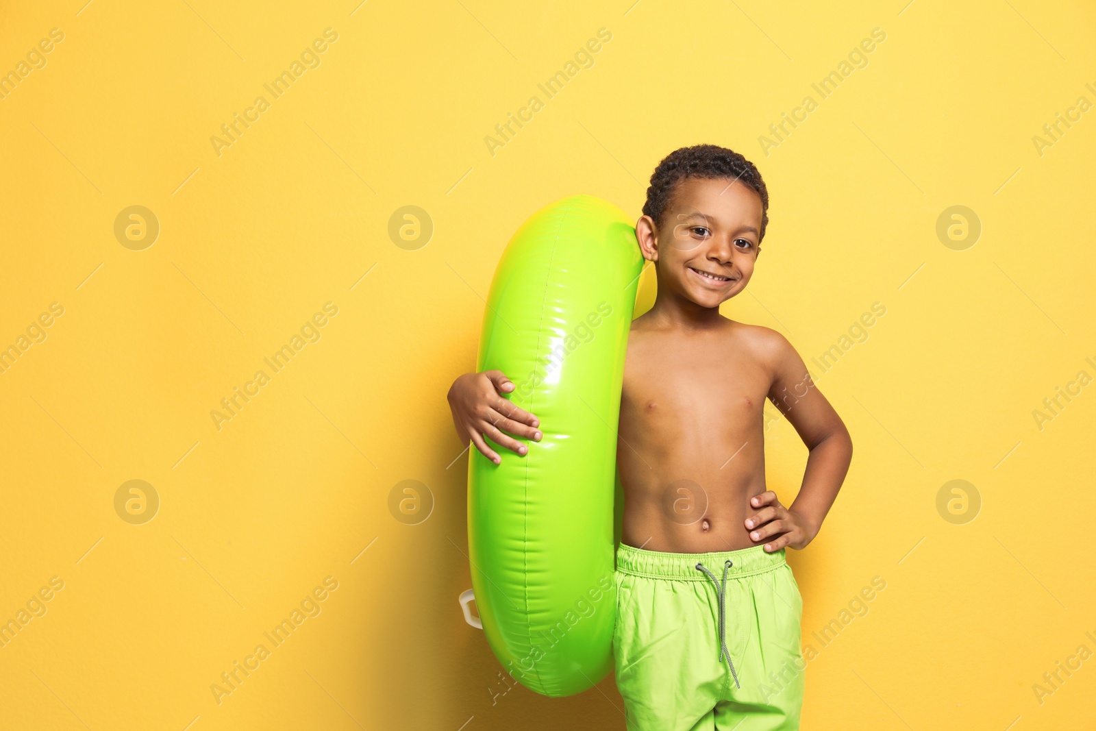 Photo of Cute African American boy with bright inflatable ring on color background