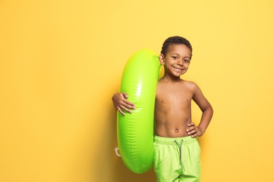 Cute African American boy with bright inflatable ring on color background