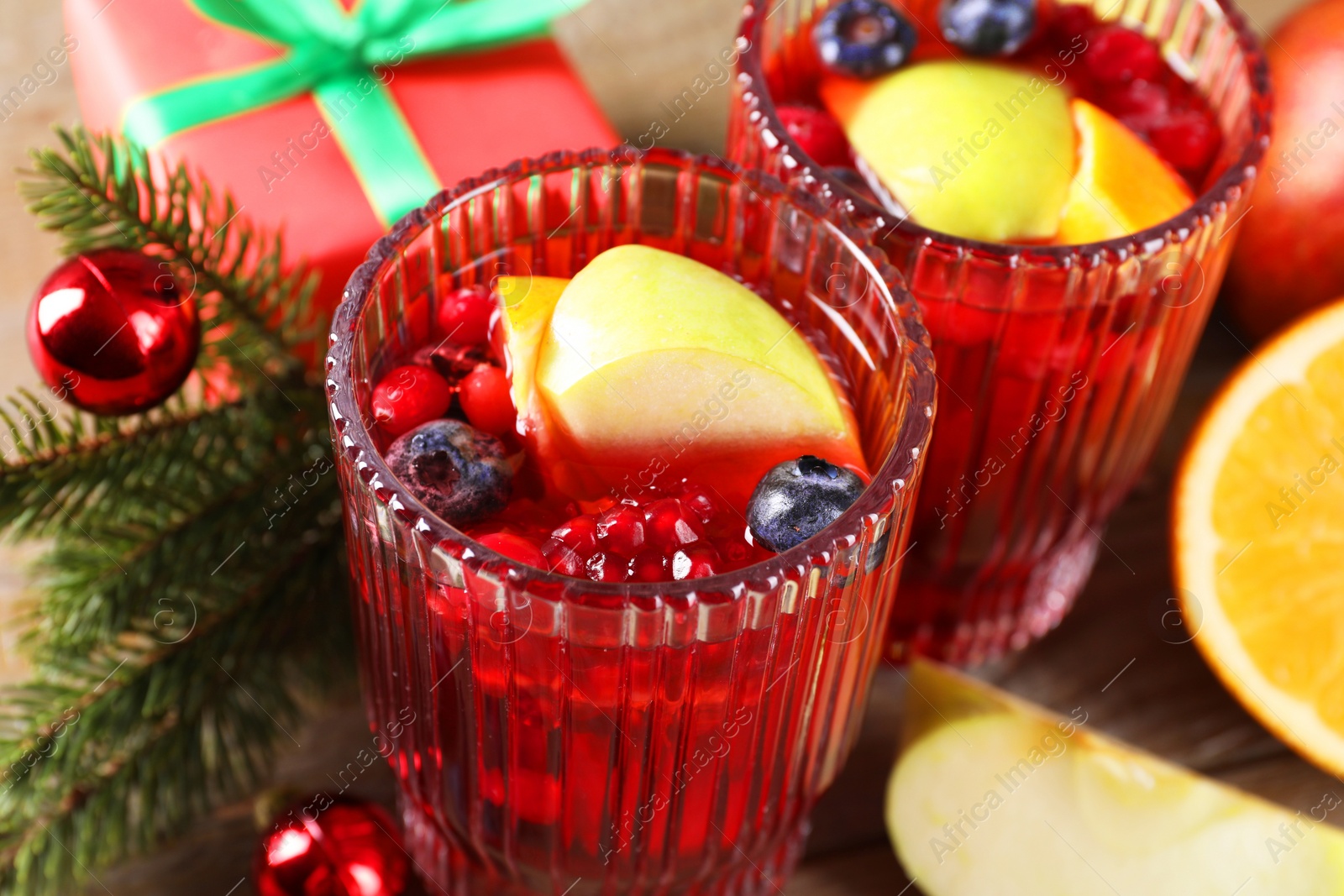 Photo of Aromatic Christmas Sangria drink in glasses on table, closeup