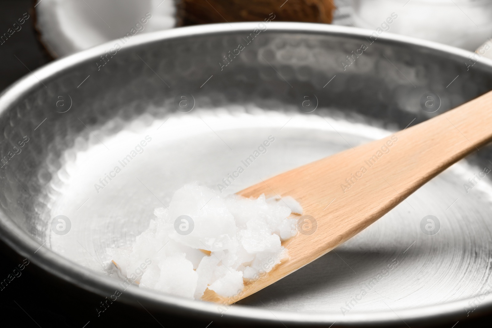 Photo of Frying pan with coconut oil and wooden spatula, closeup. Healthy cooking