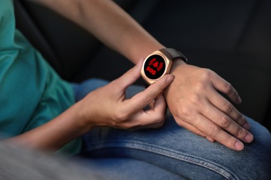 Image of Woman using SOS function on smartwatch in car, closeup
