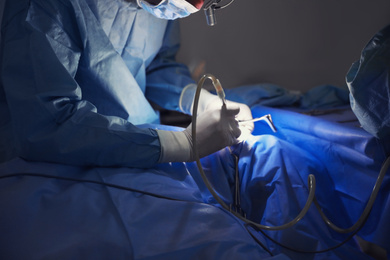 Photo of Professional doctor performing operation in surgery room, closeup