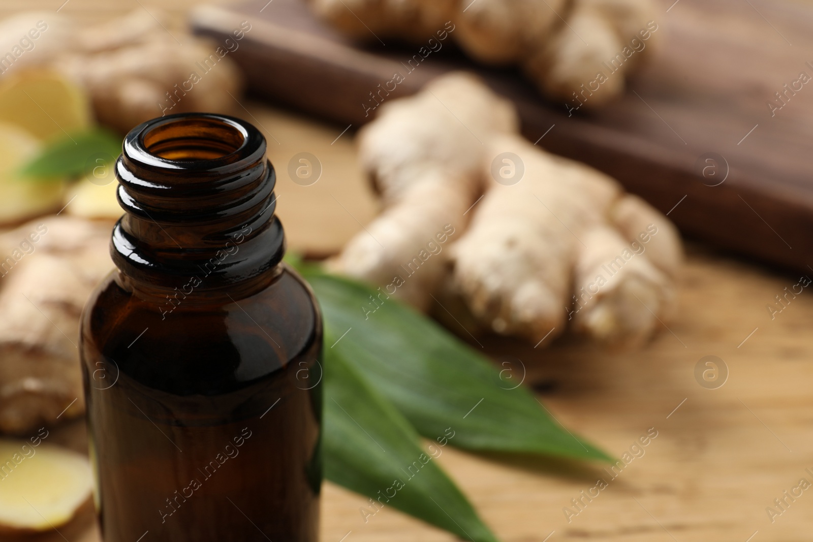 Photo of Glass bottle of ginger essential oil on table, closeup. Space for text