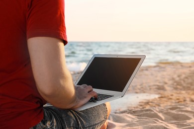 Photo of Man working with laptop on beach, closeup