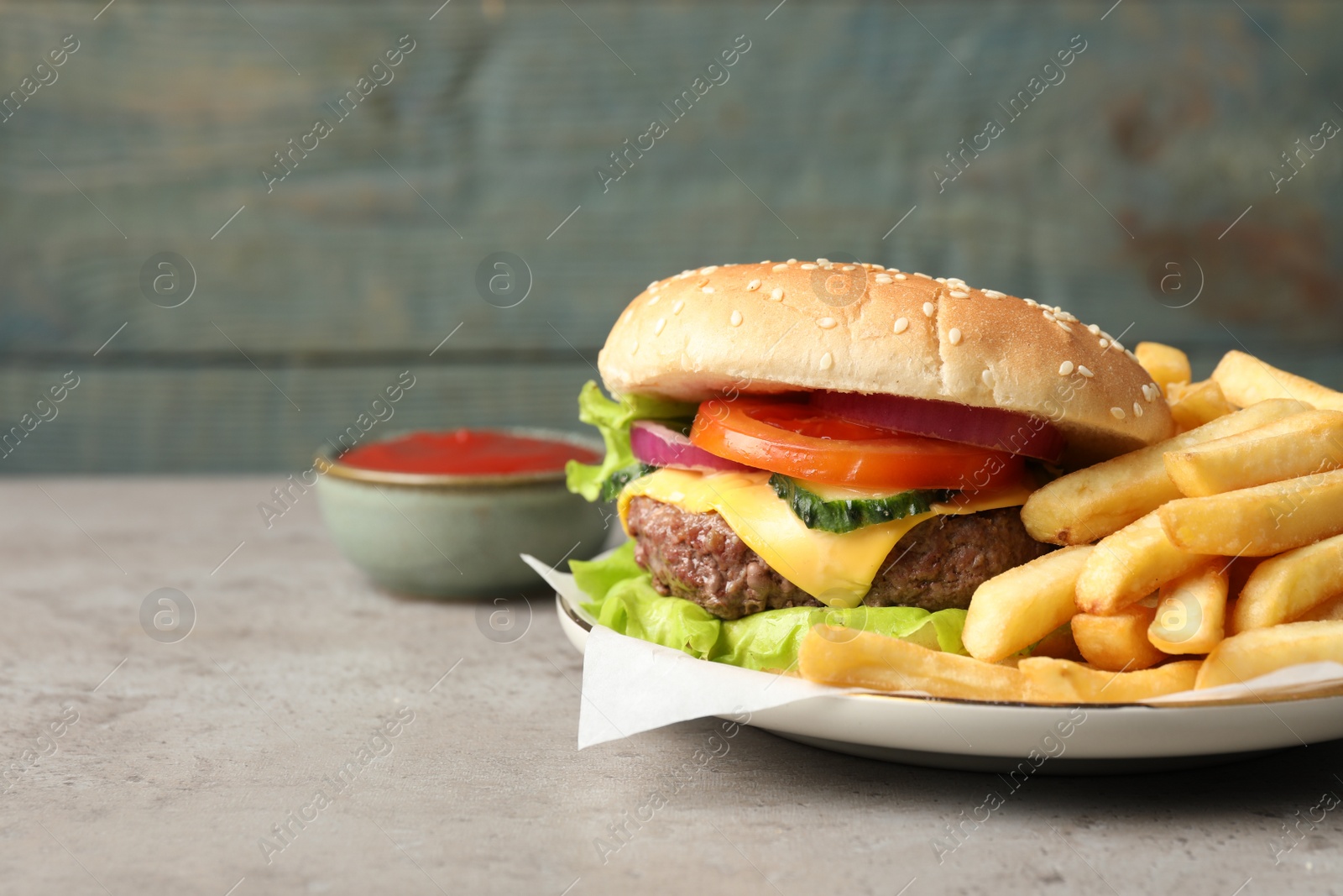 Photo of Delicious burger, ketchup and french fries served on grey table. Space for text