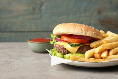 Delicious burger, ketchup and french fries served on grey table. Space for text