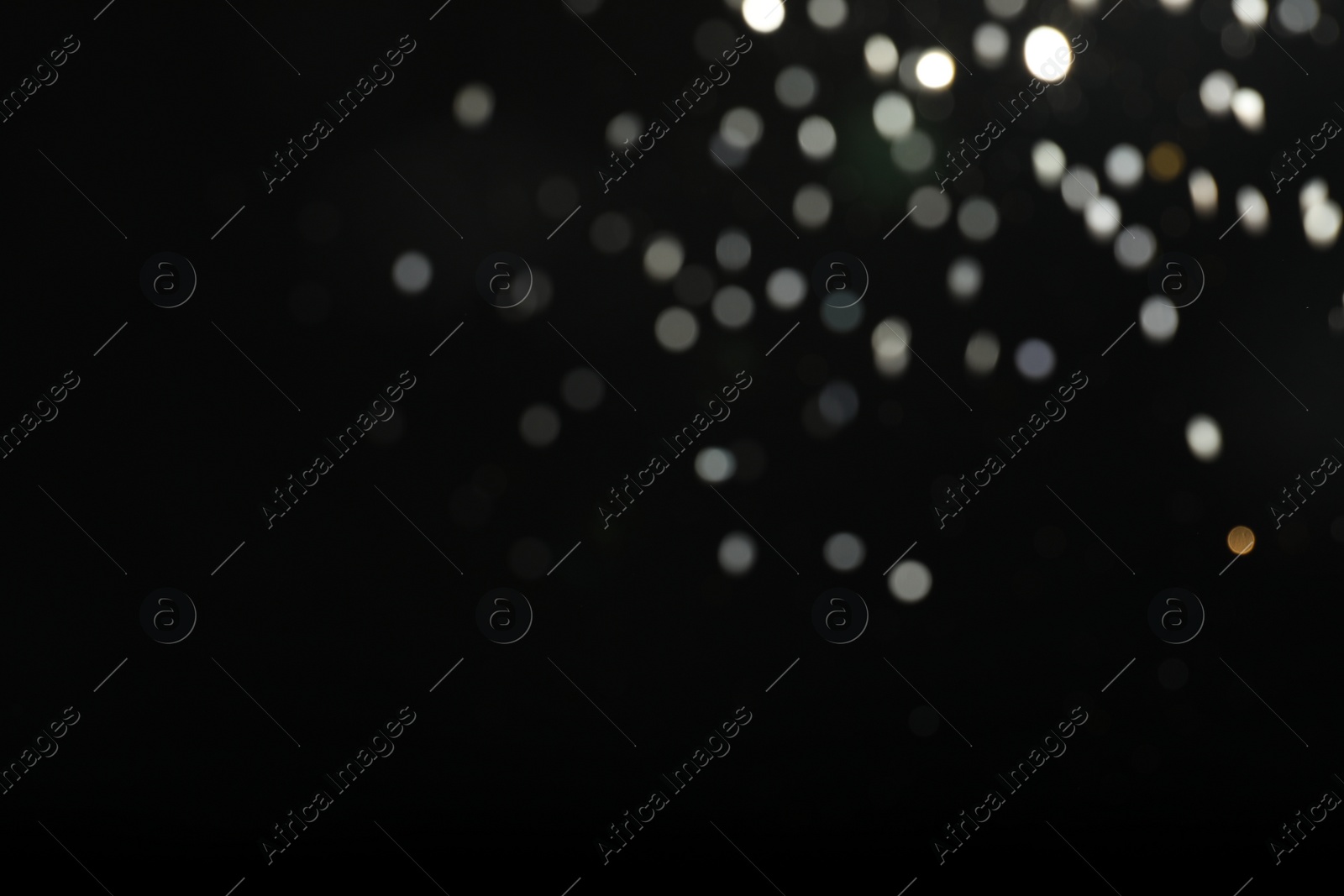 Photo of Blurred view of festive lights on black background. Bokeh effect