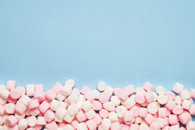 Photo of Delicious marshmallows on light blue background, flat lay. Space for text