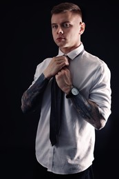 Photo of Young man with tattoos wearing shirt and tie on black background