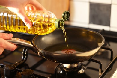 Photo of Vegetable fats. Woman pouring oil into frying pan on stove, closeup