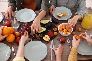 Photo of Friends eating vegetarian food at wooden table indoors, closeup