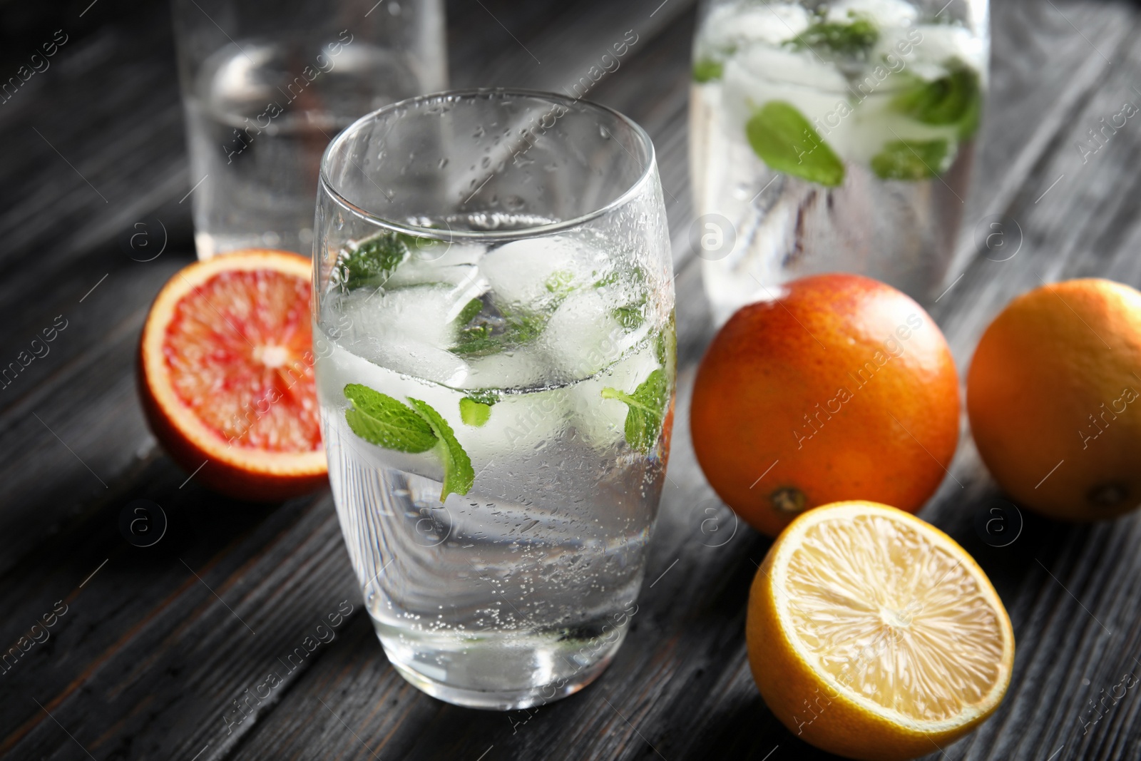 Photo of Glass of drink with ice cubes and fruits on wooden table