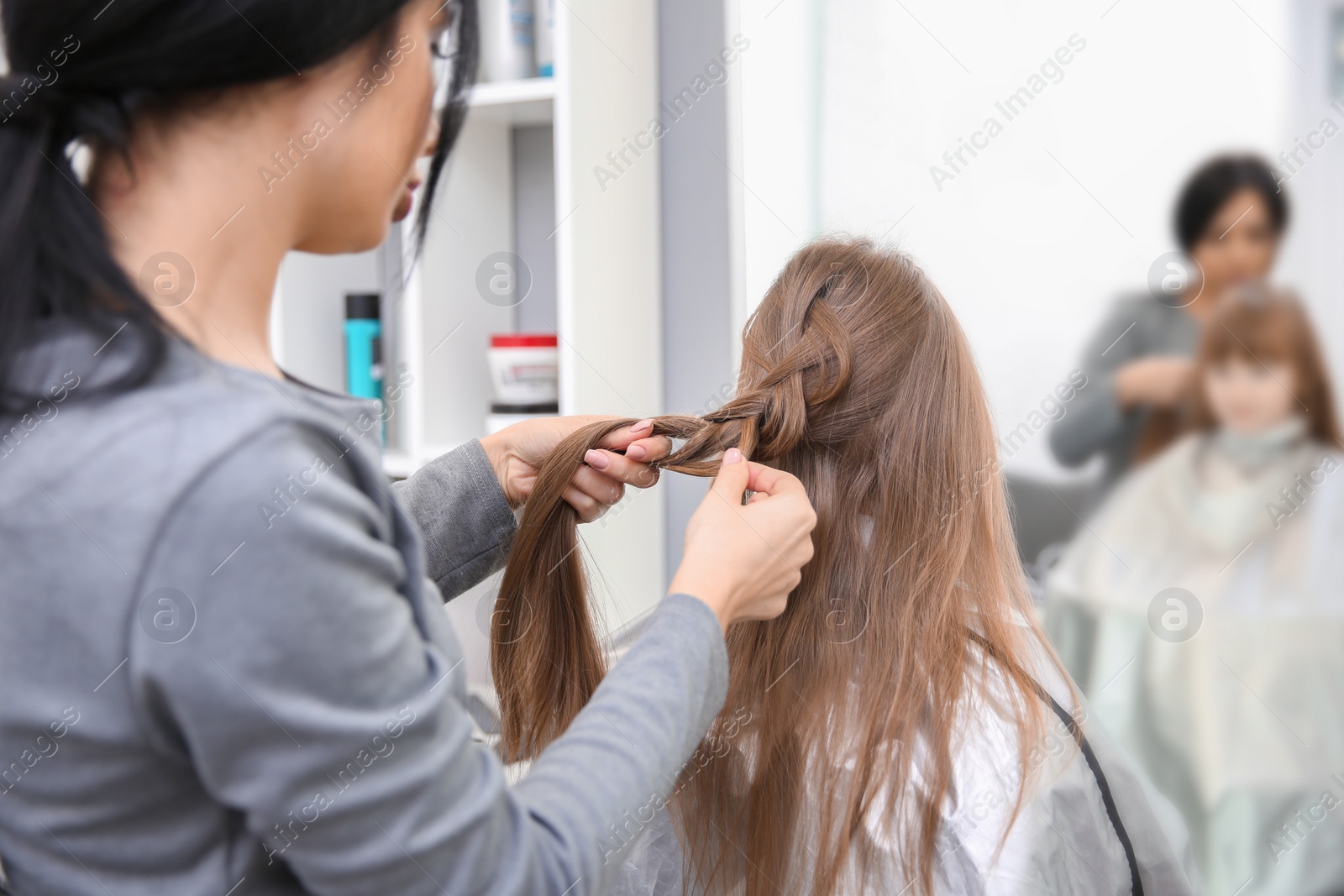 Photo of Professional female hairdresser working with little girl in salon