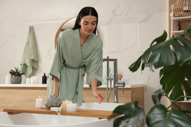 Photo of Beautiful young woman near tub in bathroom