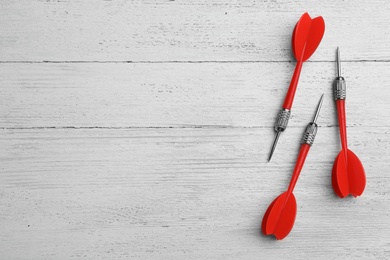 Photo of Red dart arrows on white wooden table, flat lay with space for text